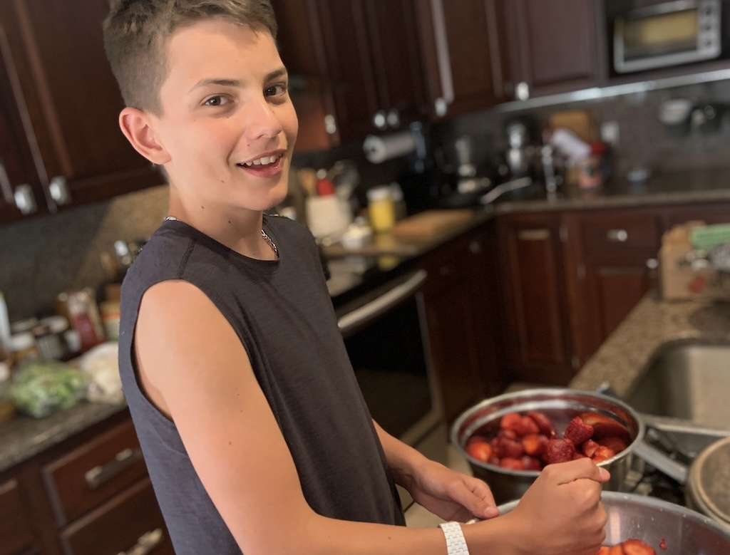 Teenager is cooking with strawberries
