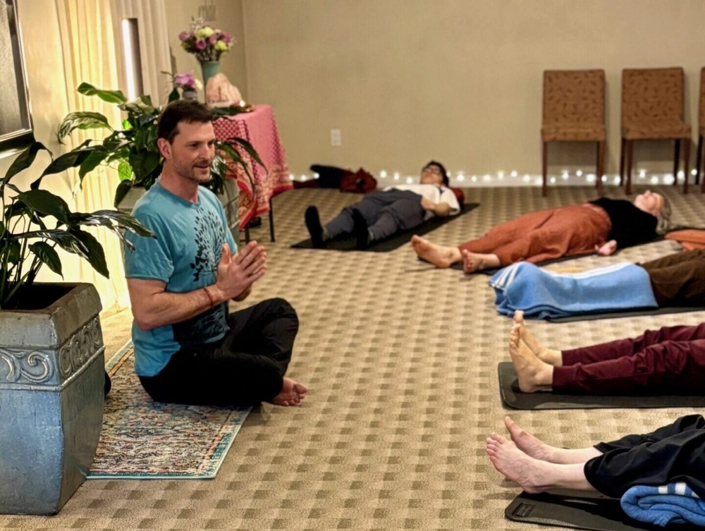 Yogesh guiding students as they relax during a gentle yoga class