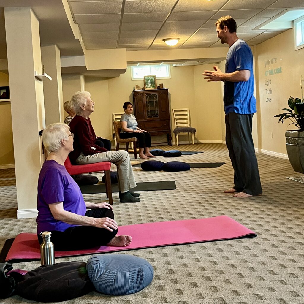 AT THE CORE YOGA studio seniors yoga class using chairs to aid seniors and make yoga easier.