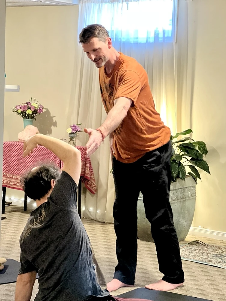 Yogesh helping a student during a gentle senior's yoga class