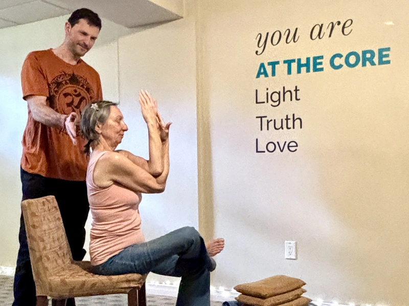 Senior practising chair yoga with instruction at AT THE CORE studio in London, Ontario